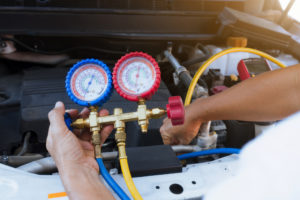 Auto mechanic using gauge air conditioning pressure in auto vehicle.